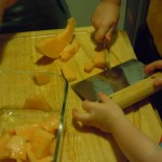 Bl using the bench scraper to scoop up the melon pieces
