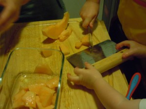 Bl using the bench scraper to scoop up the melon pieces 